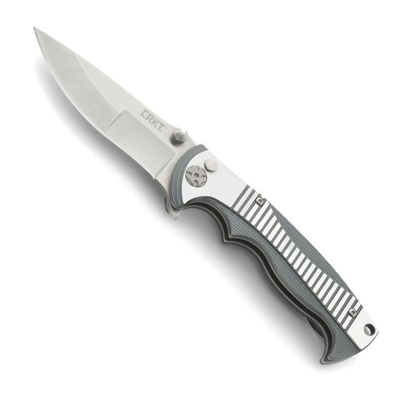 Nóż Składany CRKT 5290 Tighe Rade Nóż CRKT ze składanym ostrzem (folder) wyposażony jest w gładkie ostrze Drop Point. Ten typ ostrza ma bardzo dobre właściwości tnące oraz wytrzymały czubek. Drop Point jest szczególnie przydatny w nożach myśliwskich i roboczych ogólnego przeznaczenia. Ostrze wykonano ze stali nierdzewnej 8Cr13MoV. Ma twardość 58-60 HRC. Rękojeść posiada okładziny - LifeGun.pl Nóż składany CRKT 5290 Tighe Rade-1
